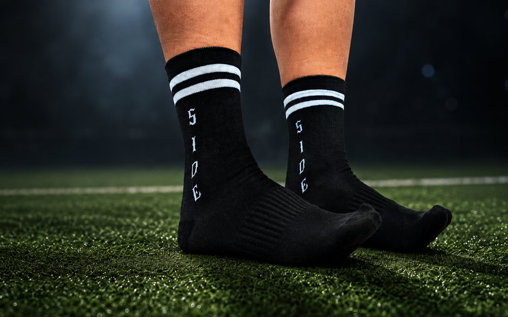 Athlete on a turf field wearing black custom athletic crew socks with white stripes