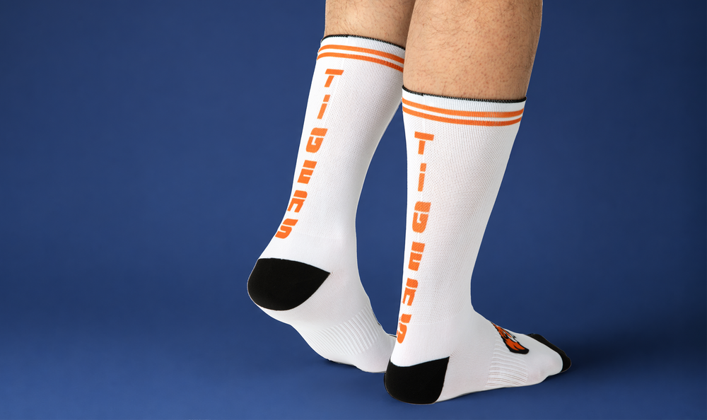 Custom basketball socks in white with orange Tigers team lettering on a blue background