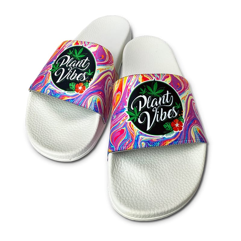 White custom slides with a Plant Vibes logo on colorful swirl-pattern straps