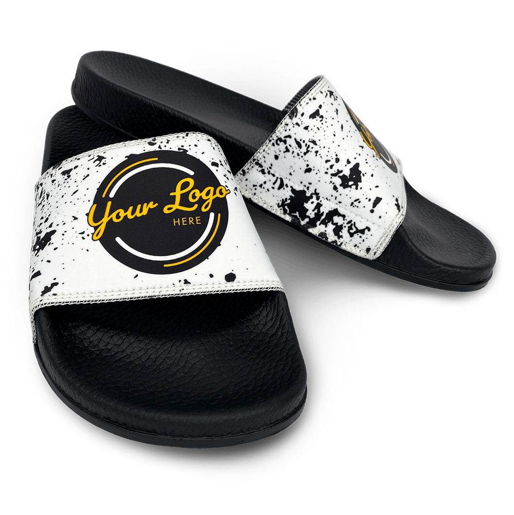 Slide sandals with black soles and a white strap with black splatters and generic 'Your logo here' logo